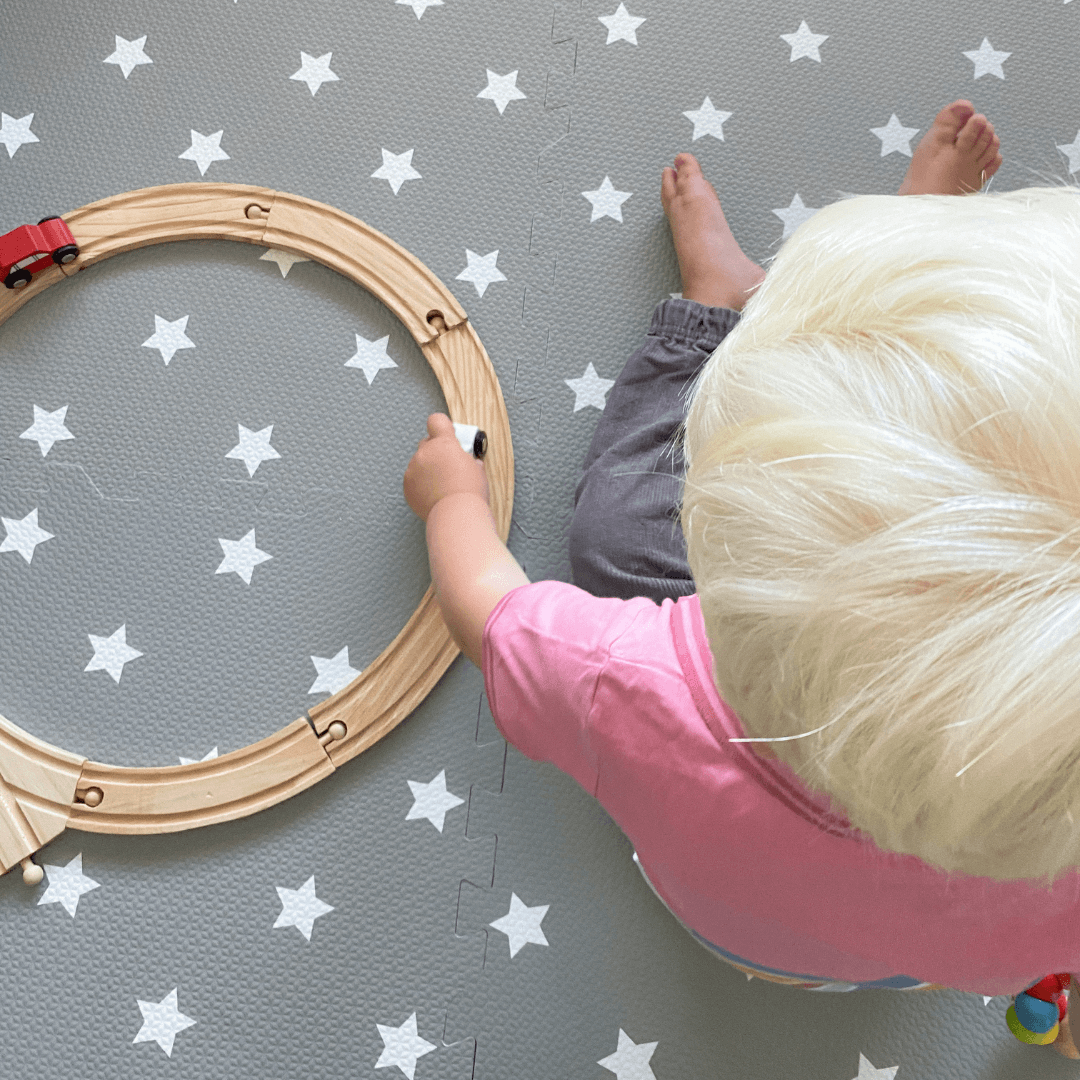 child playing on the Grey with white stars play mat, set up in a play space in the home. 