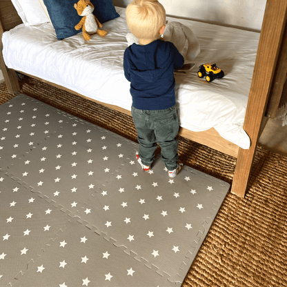 Toddler playing on the Grey with white stars play mat, set up in a play space in the home.