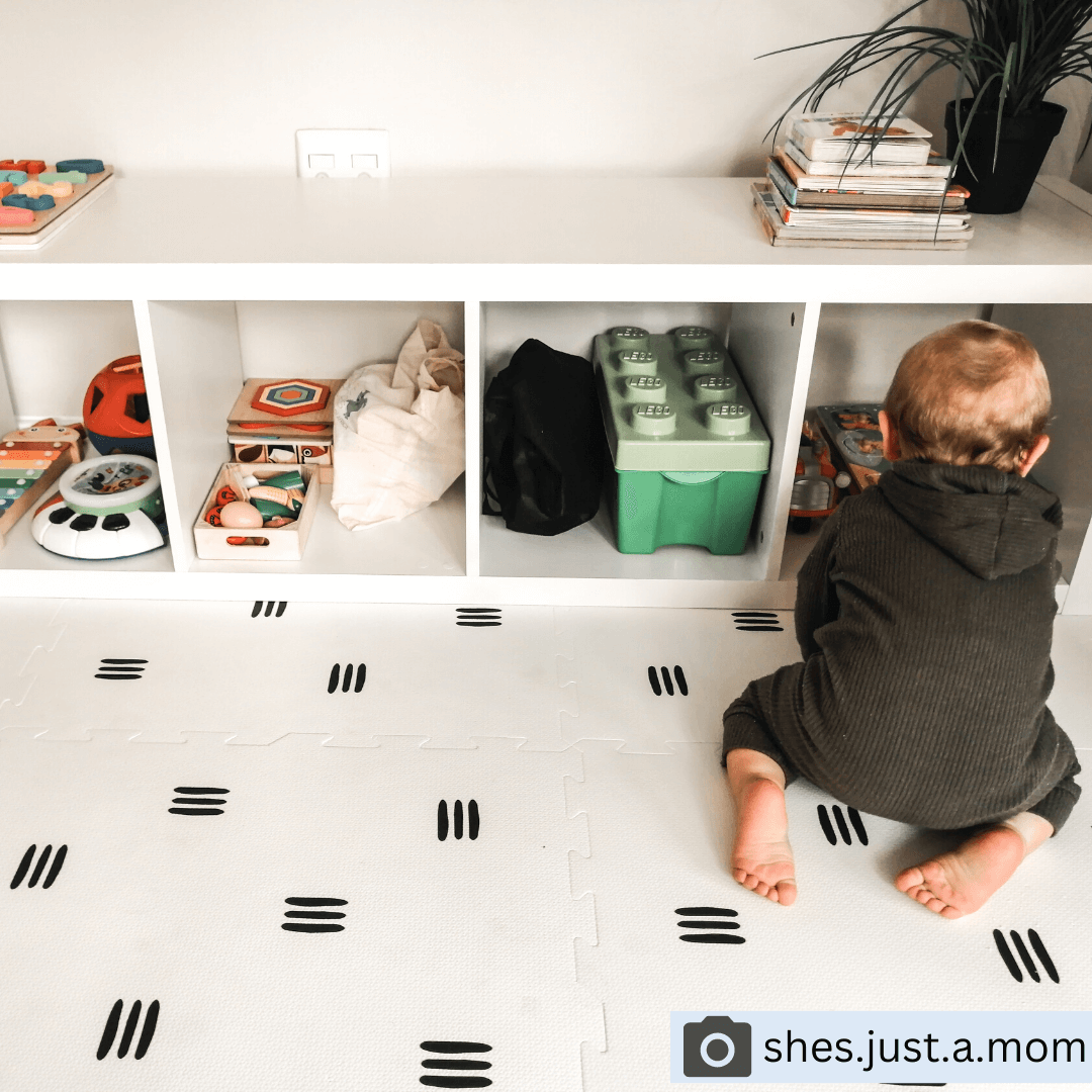 Child having fun while playing on the White with black stripes play mat, set up in a child’s play space, featuring a sleek design from the Maxie and Moo luxury collection