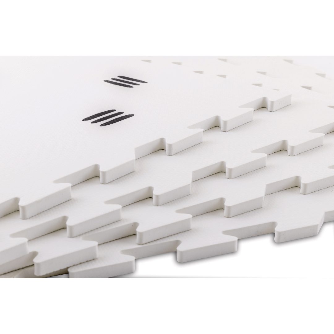 Stacked tiles from the White with black stripes play mat, showcasing its thickness and high-quality construction made from soft, padded EVA foam.
